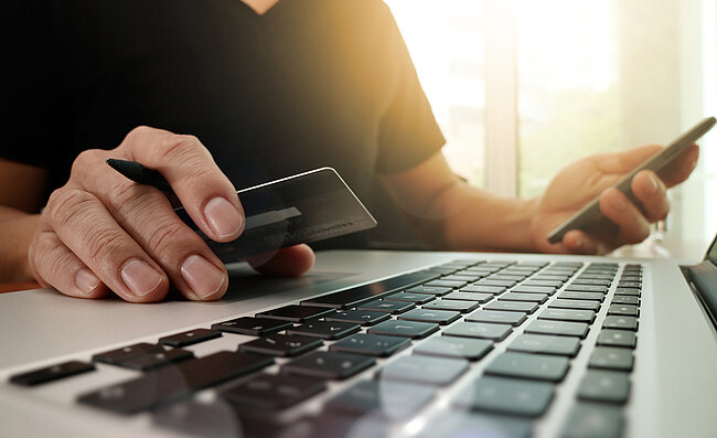 Un homme assis devant un ordinateur avec une carte de crédit