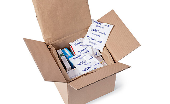 Image of an open shipping box containing medications and ice packs.