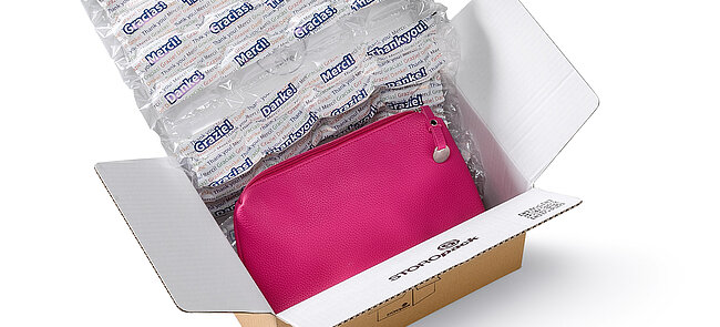 Un carton contenant un sac rose et des coussins d’air avec motif imprimé