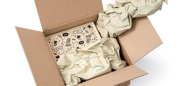 Un carton contenant une boîte en bois et des bandes de rembourrage en papier végétal
