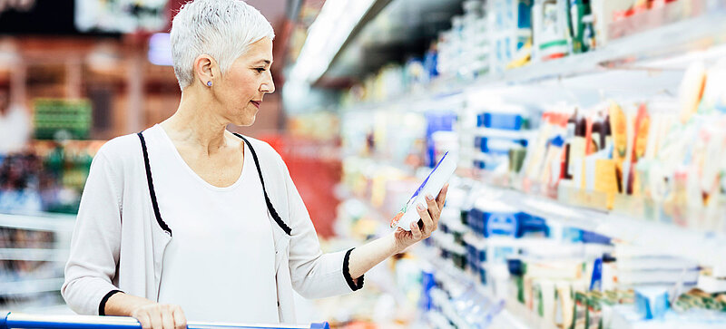 Une femme devant le rayon frais d’un supermarché